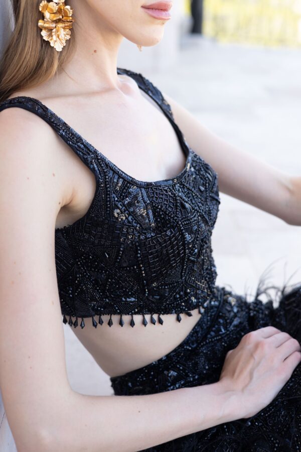 A woman wearing a black sequined Alinia dress and earrings.