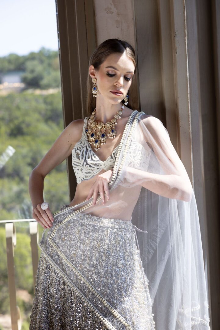 A woman in a silver Rushi posing on a balcony.