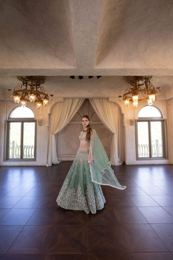 A bride in a green Pixia standing in a large room.