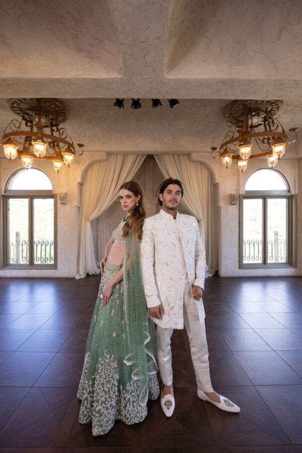 A bride and groom posing in a room with Pixia chandeliers.