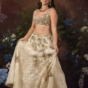 A woman in a PERLA cream and gold lehenga posing for a photo.
