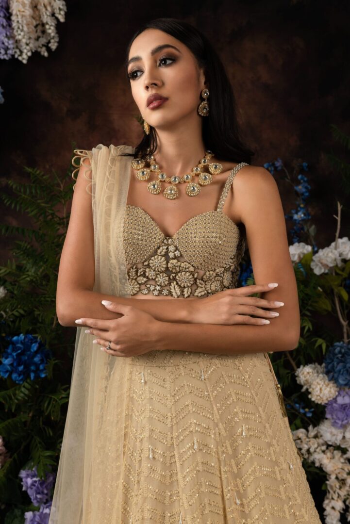 The model is wearing a beige GIGI with a gold embroidered dupatta.