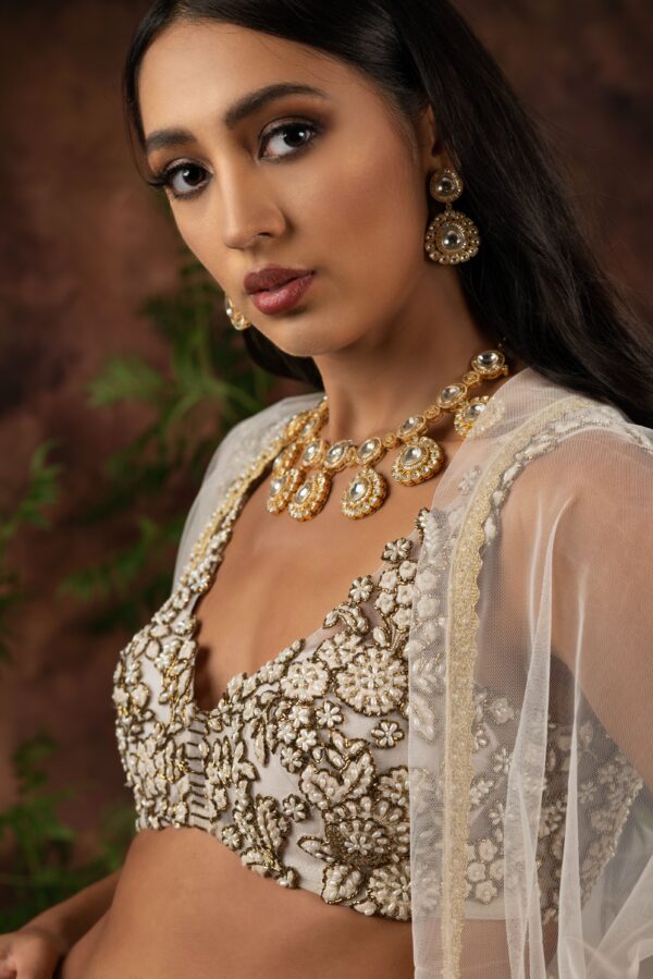 An indian woman wearing a white and gold Niaa set.