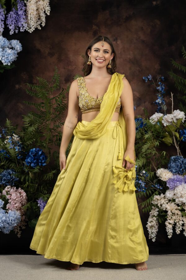 A woman in a yellow Miraya posing in front of flowers.