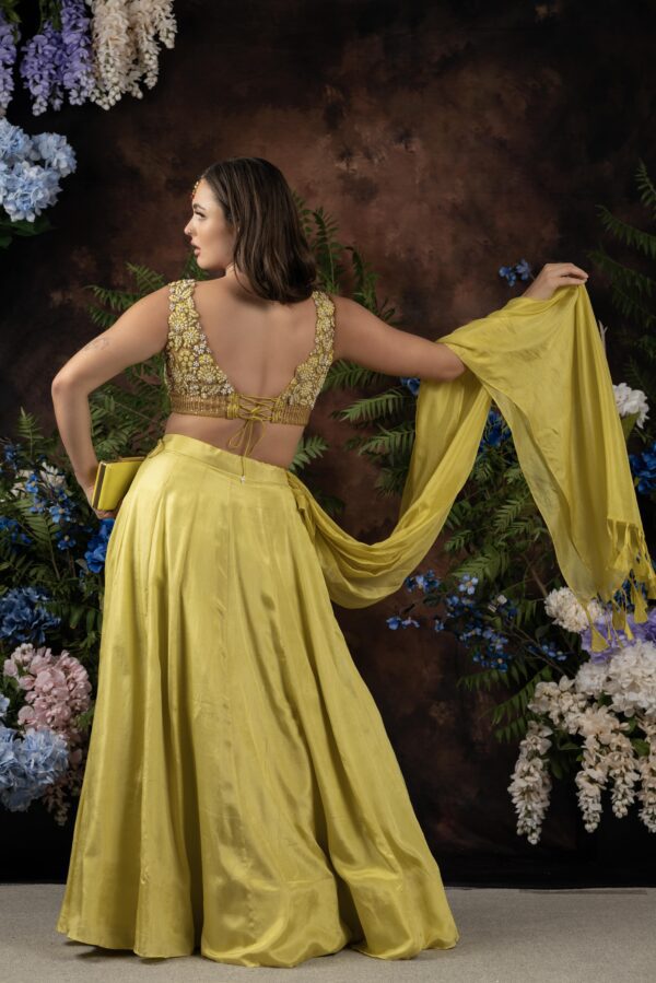 The back view of a woman wearing a yellow Miraya lehenga and dupatta.